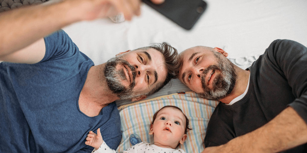 two fathers with their child taking photos with a camera with bright lights