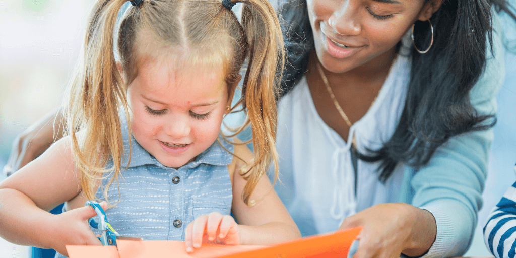 child with adult cutting paper