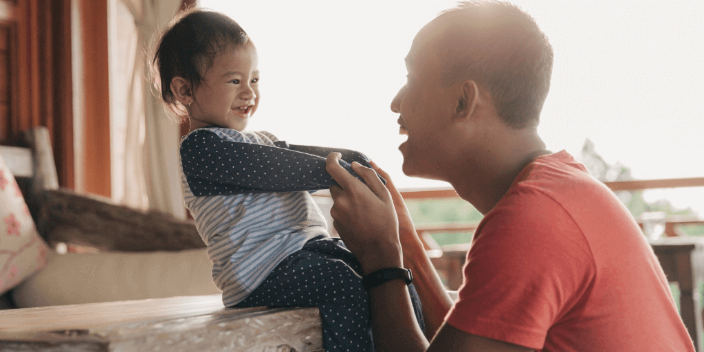 Father smiling at child while holding hands