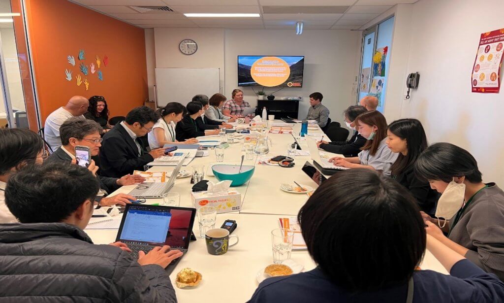 People around a boardroom table with laptops.