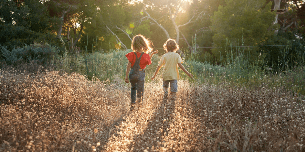 Two children with their backs to the camera exploring nature