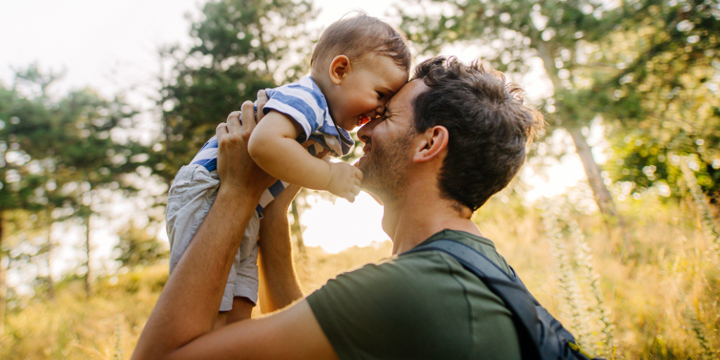 Father happily lifting his son up at a park