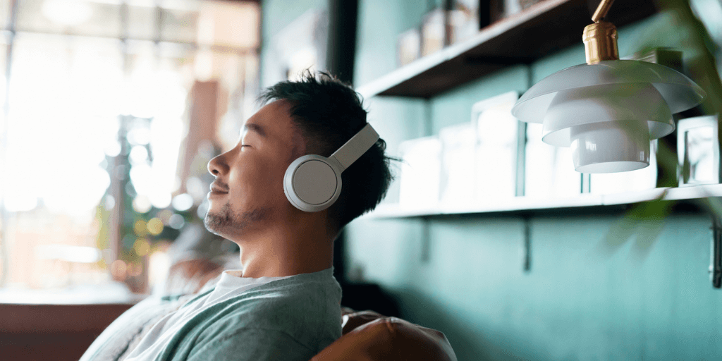 Man smiling as he meditates on a couch wearing headphones